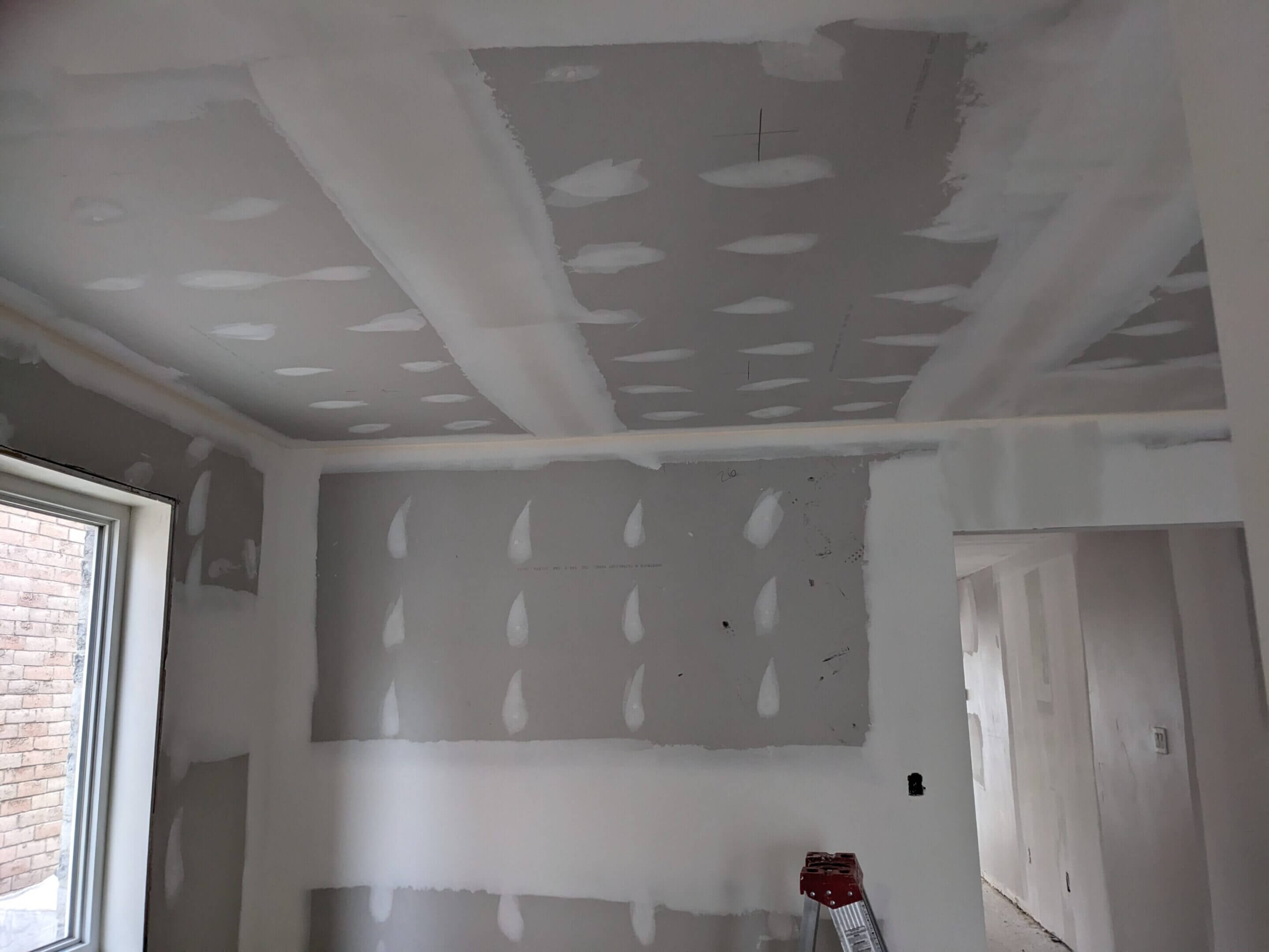 Interior room under construction with drywall installed and taped.