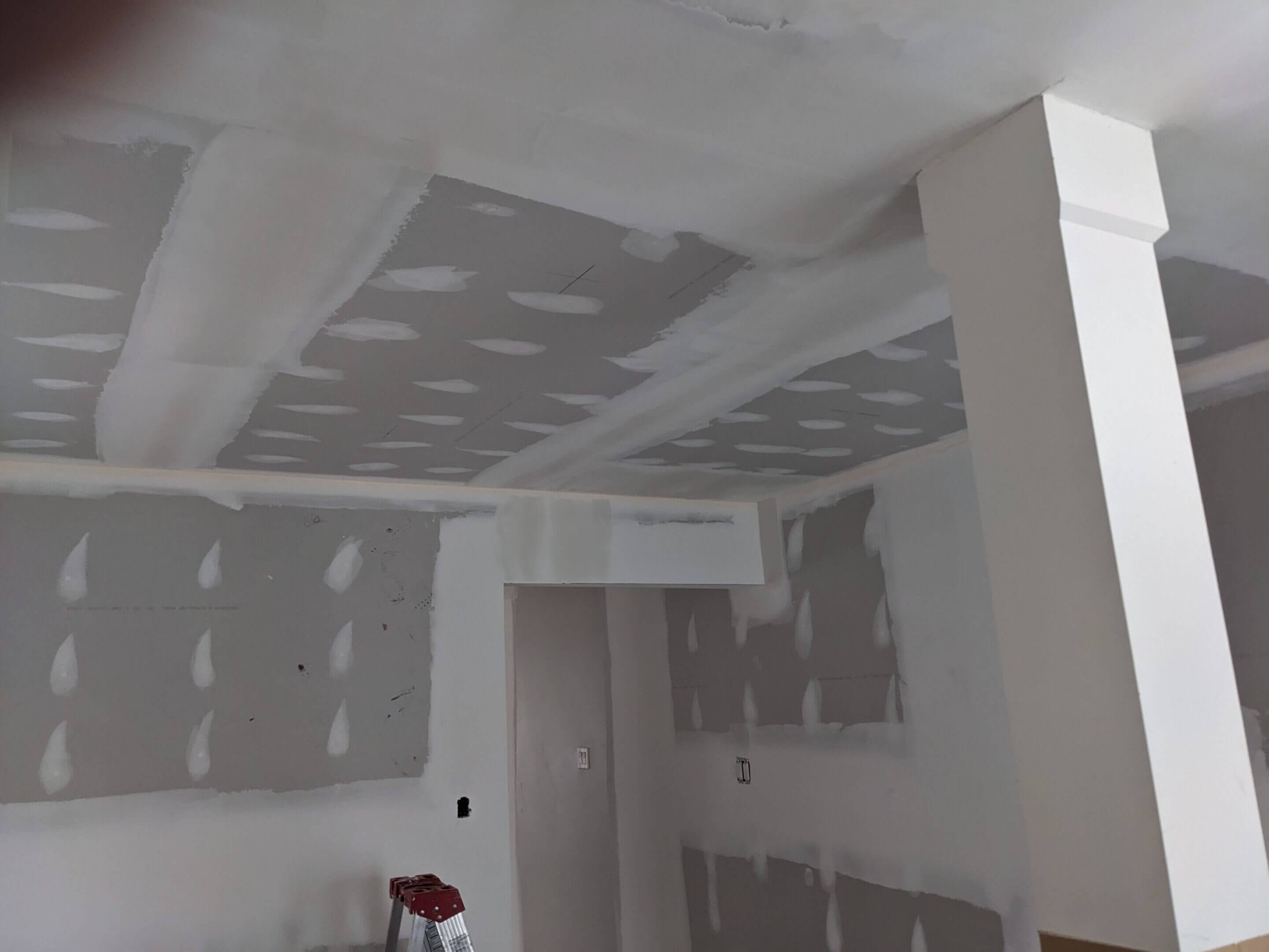 Unfinished drywall installation in a room under construction.