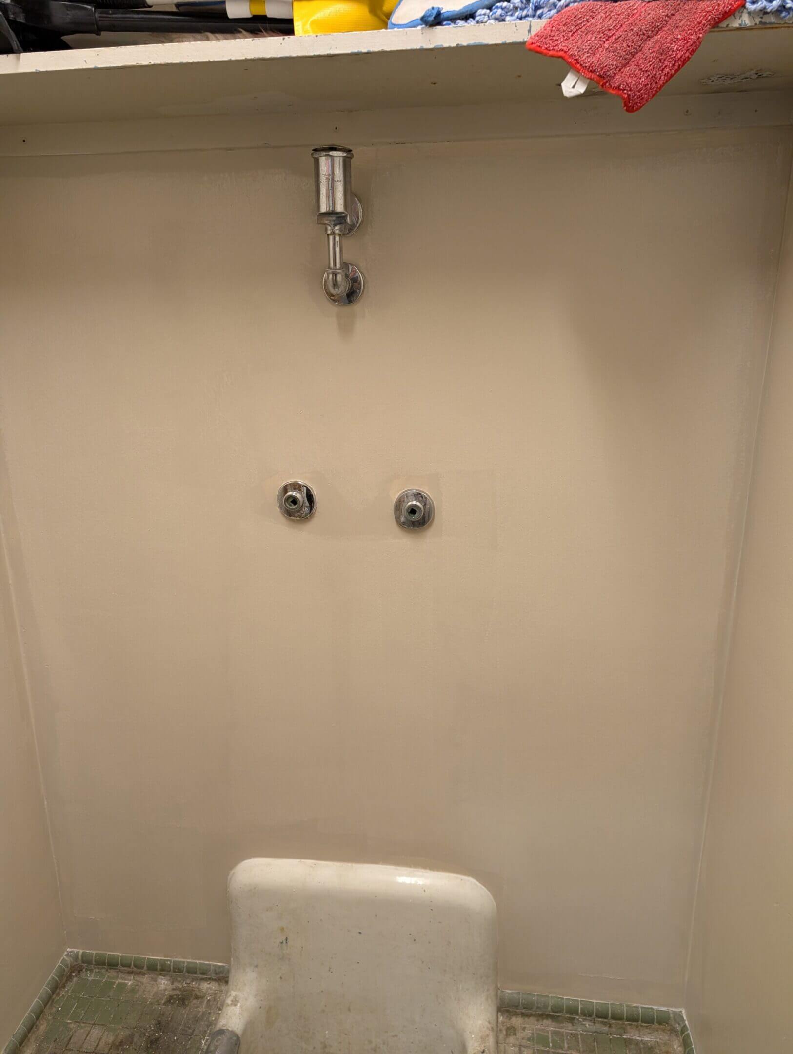 Empty shower stall with two knobs and a soap dish.